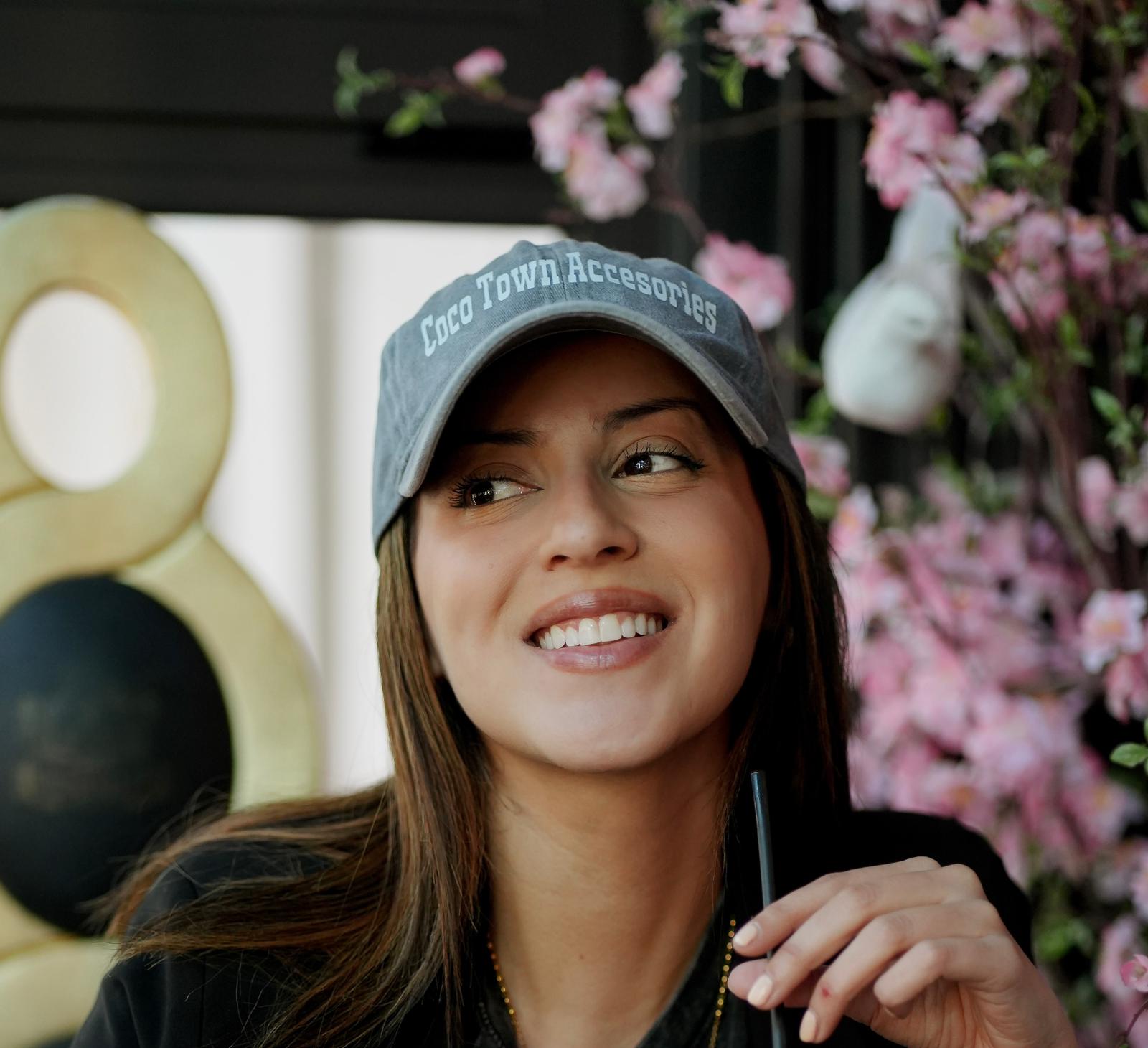 Gloria sonriendo con gorra entre flores rosadas