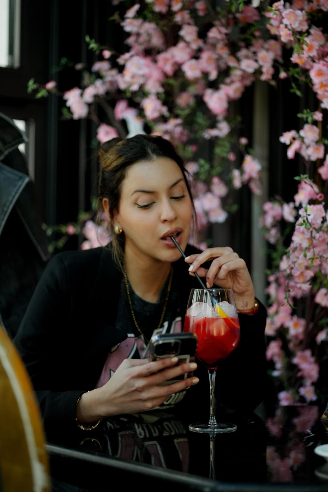 Gloria con un spritz entre flores rosadas